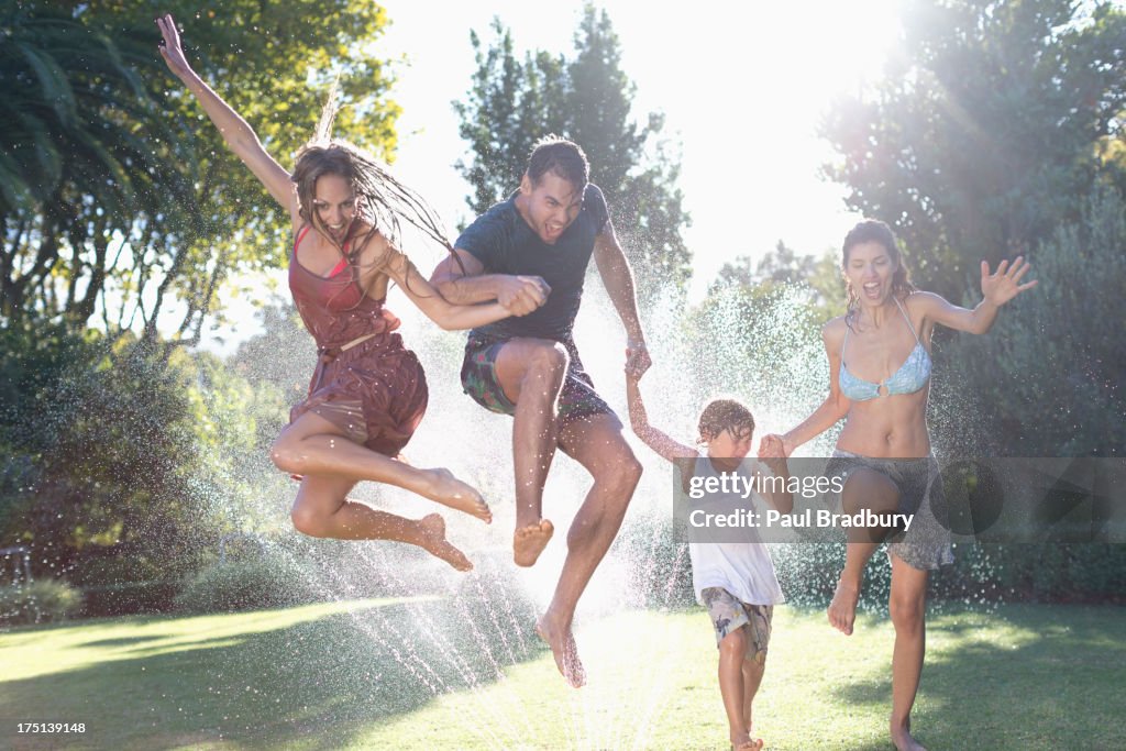 Familie springen in Rasensprenger