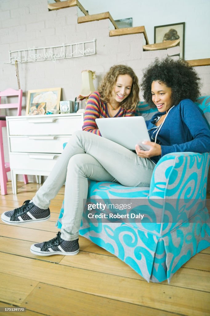 Women using laptop together in armchair