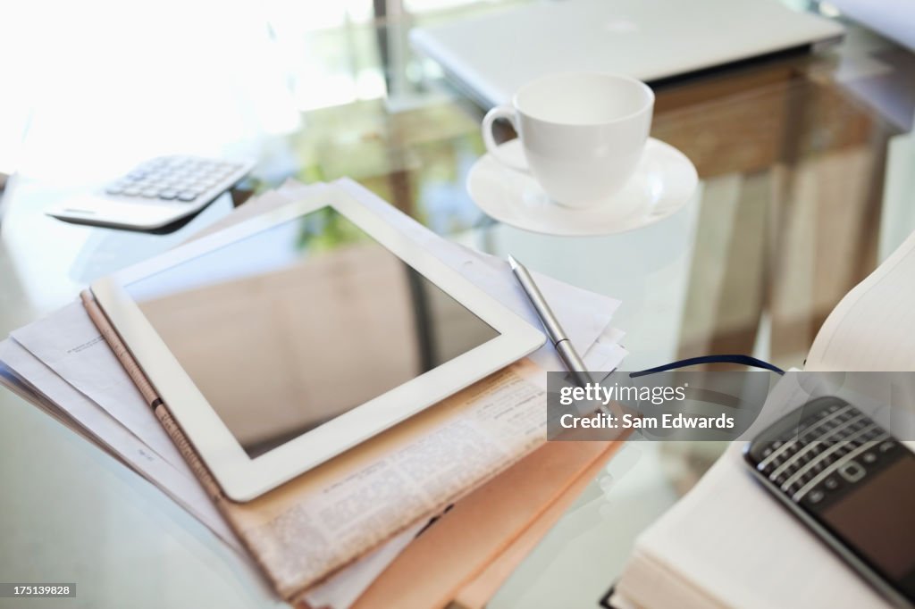 Tablet computer, newspaper, coffee cup and cell phone on desk