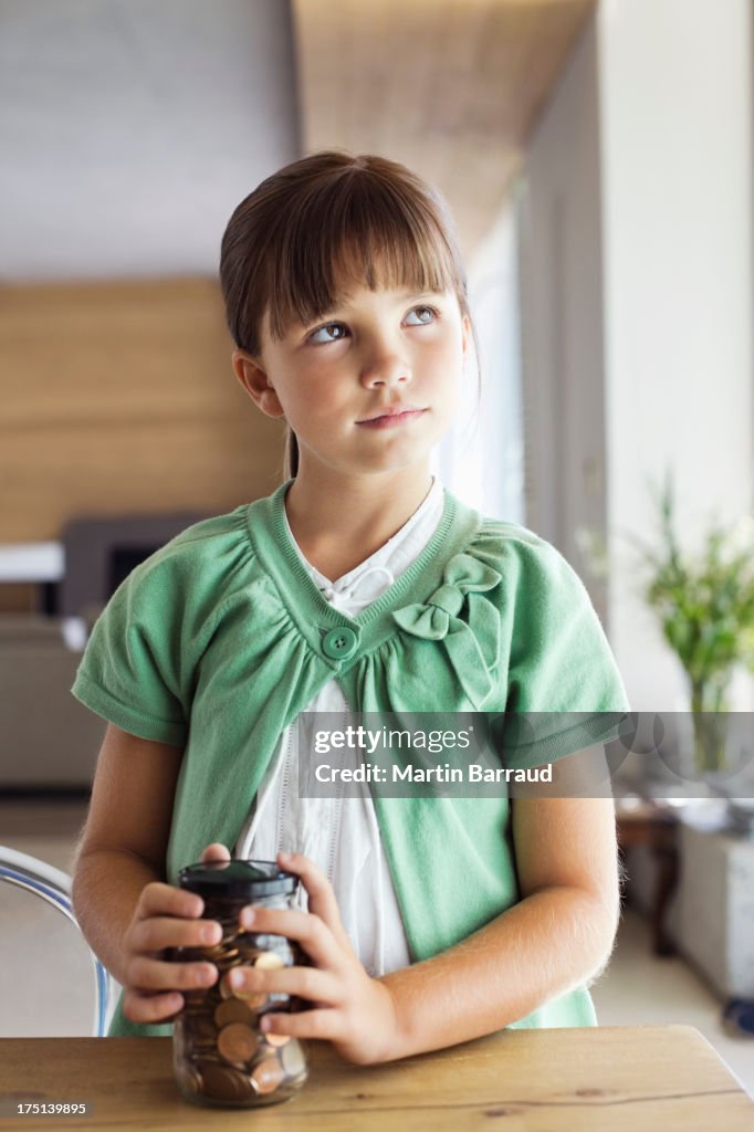 Girl holding change jar at table