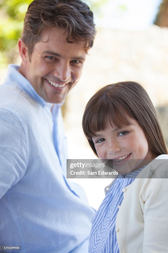 Père et fille souriant à l'extérieur