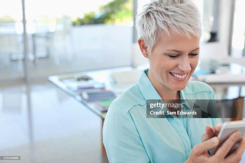 Businesswoman using cell phone in office