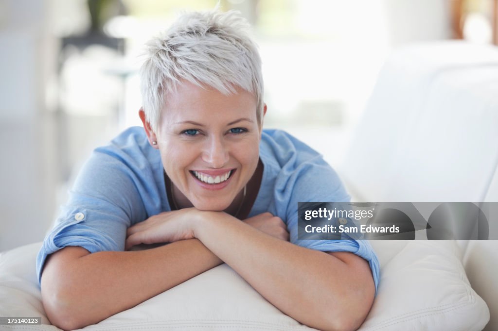 Woman resting chin in hands on sofa
