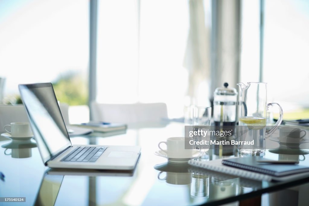 Laptop, coffee cups and notebooks on desk