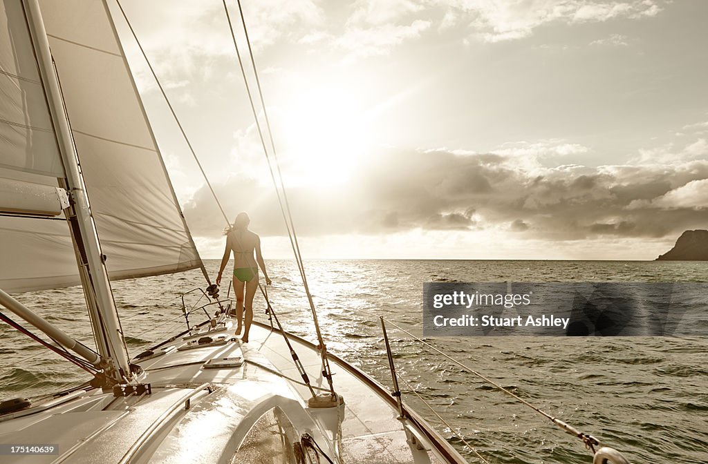 Female on bow of sailing yacht, Whitsundays sunris