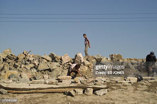 Photo taken on August 19, 2012 shows a man walking on rubble next to a roadside near a 'toxic lake' on the outskirts of the inner Mongolian city of...