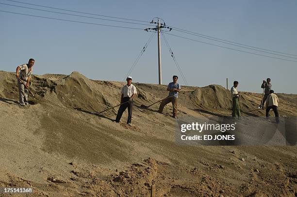 In a photo taken on August 19, 2012 workers stand on a roadside near a 'toxic lake' surrounded by rare earth refineries near the inner Mongolian city...