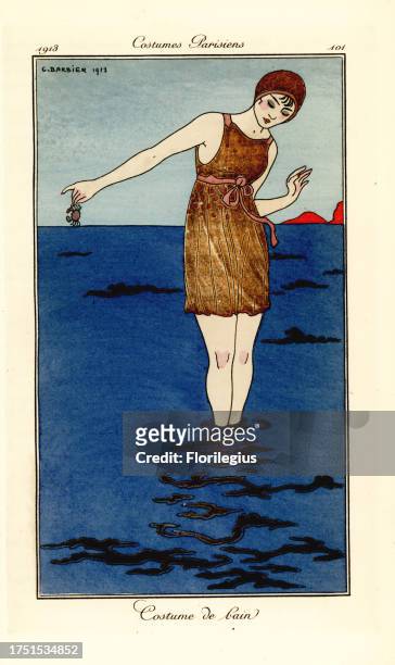 Woman in swimming costume up to her ankles in the sea on a beach holding a crab. Costume de bain. Handcoloured pochoir etching after an illustration...