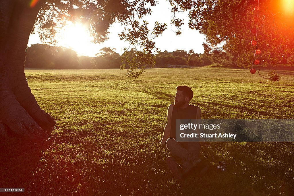 Man sitting in grassy park on sunset