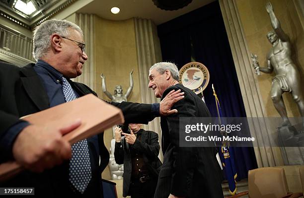 Outgoing FBI Director Robert Mueller gets a pat on his back following his farewell ceremony at the Department of Justice August 1, 2013 in...