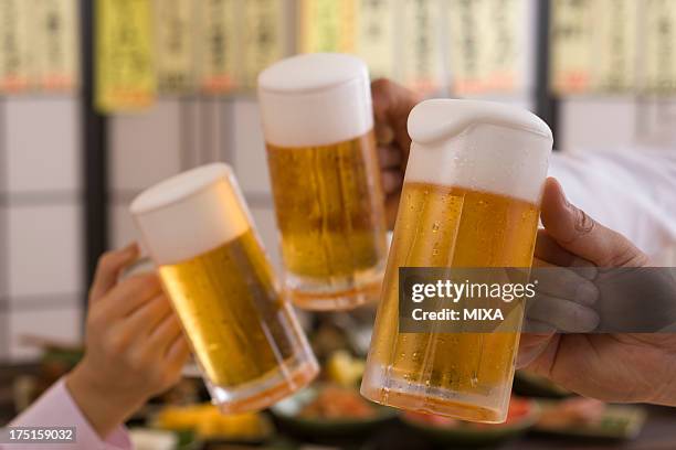 three people toasting with beer at izakaya - ビールジョッキ ストックフォトと画像