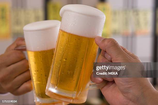 two people toasting with beer at izakaya - beer jug stock pictures, royalty-free photos & images