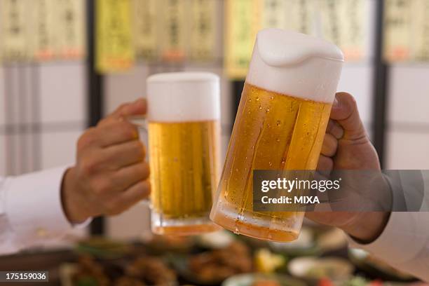 two people toasting with beer at izakaya - beer stein stockfoto's en -beelden