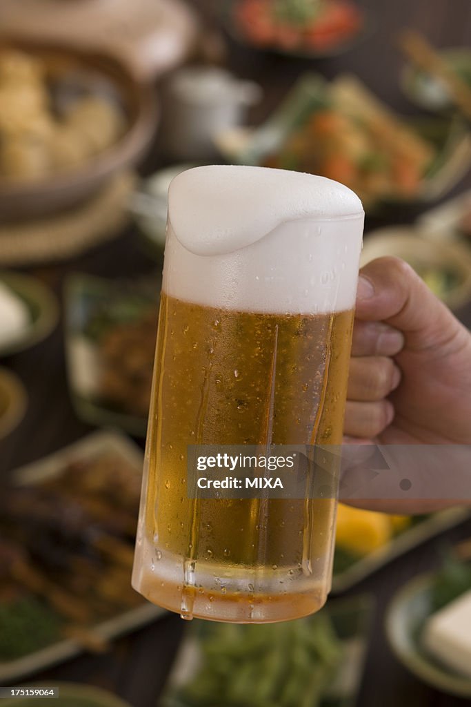 Human Hand Holding Jug of Beer at Izakaya