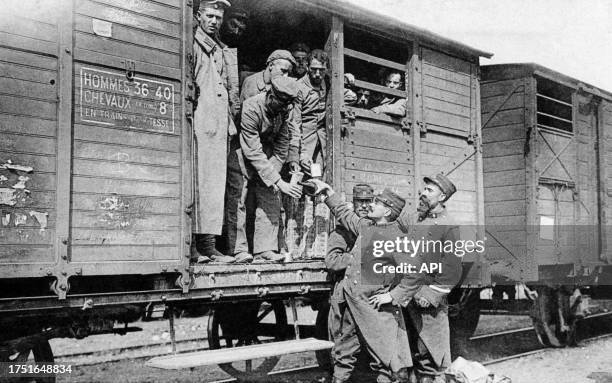 Un soldat français sert du vin à des prisonniers allemands dans un wagon de train en 1915.