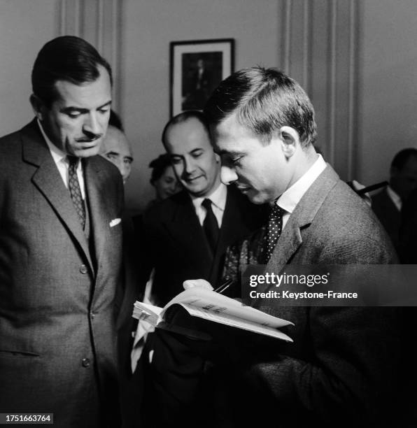 Jacques Séguéla dédicaçant son livre Jacques Séguéla présentant son livre 'La Terre en rond', le 30 mai 1961, à Paris. À Maurice Herzog, le 30 mai...