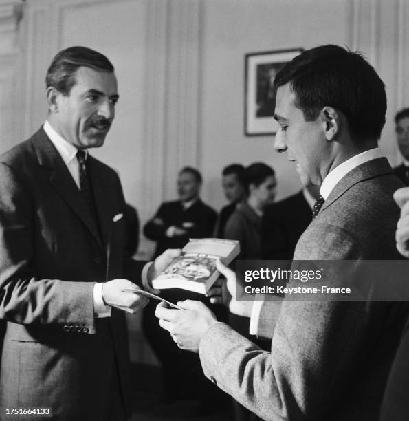 Jacques Séguéla dédicaçant son livre Jacques Séguéla présentant son livre 'La Terre en rond', le 30 mai 1961, à Paris. À Maurice Herzog, le 30 mai...