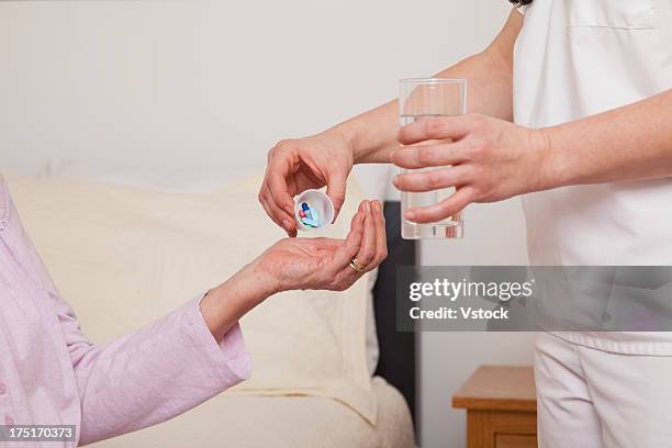 nurse giving pills to senior patient, close-up - drug bust stock pictures, royalty-free photos & images