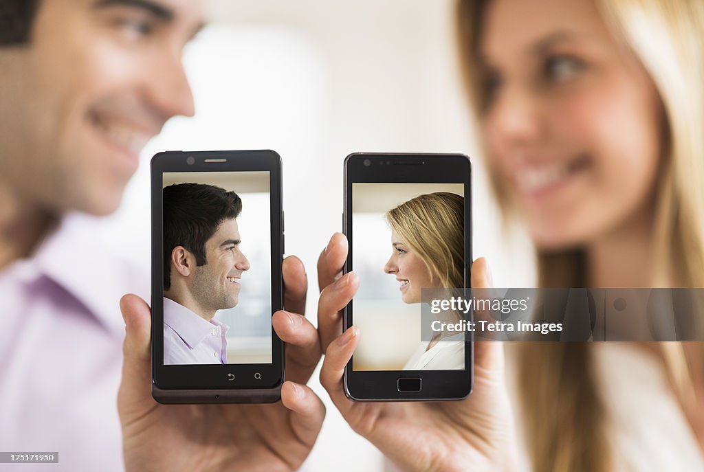 Couple holding smartphones with their pictures on
