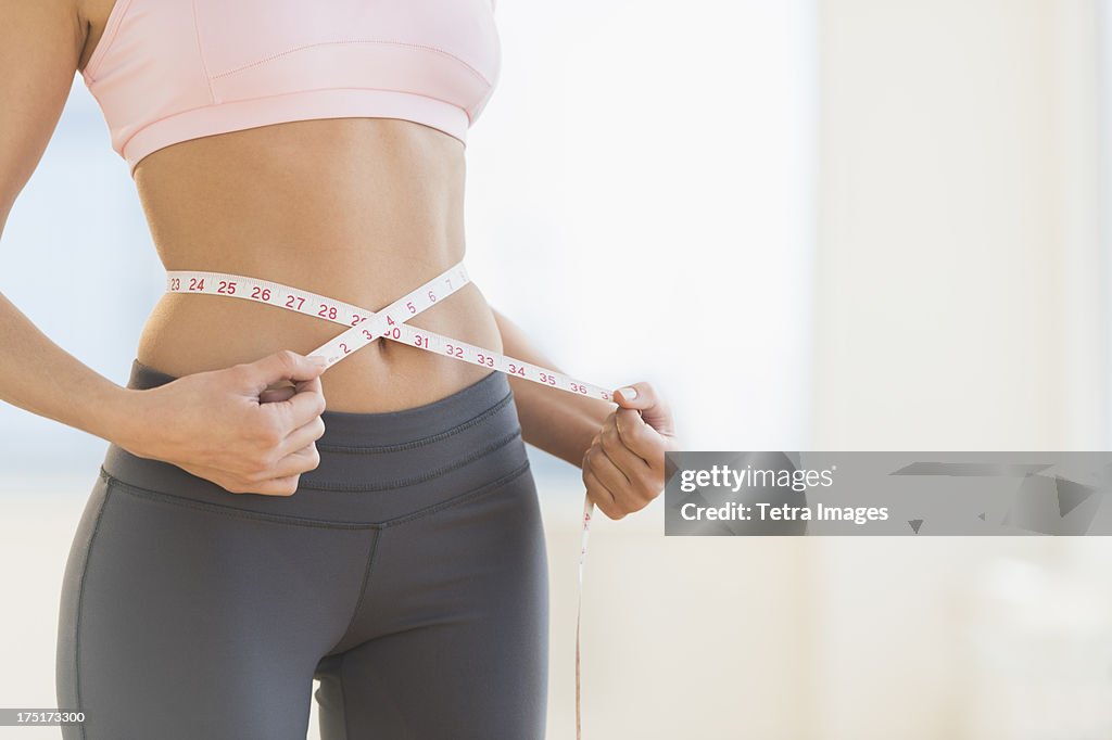 USA, New Jersey, Jersey City, Woman measuring waist