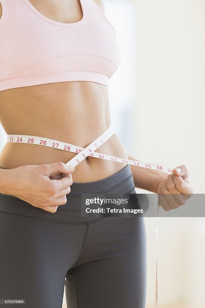 USA, New Jersey, Jersey City, Woman measuring waist