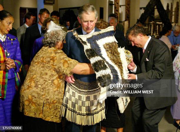 Britain's Prince Charles looks bemused as two Maori elders attempt to fit a traditional Maori grass skirt after presenting him with a Kiwi feather...