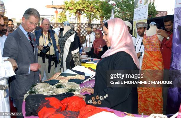 Britain's Prince Charles looks at clothes during a visit to Muscat's Sadaf market 07 November 2003. The Prince of Wales is on a five-day visit to the...