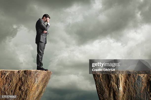 distraught businessman standing at the edge of a cliff - ravine 個照片及圖片檔