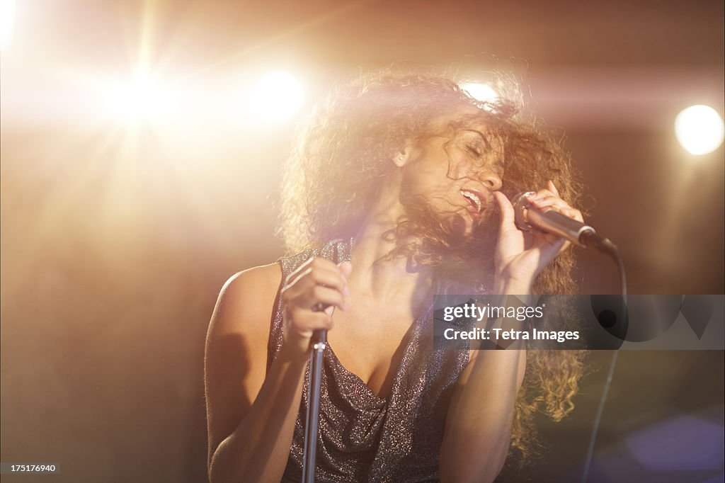 USA, New Jersey, Jersey City, Young woman singing in spotlight