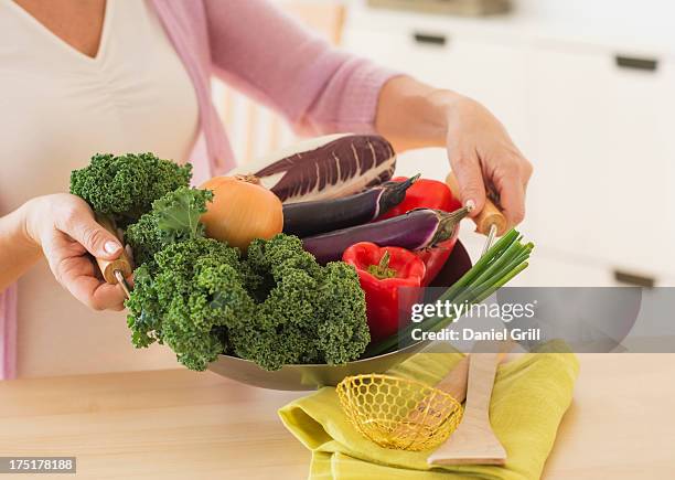 usa, new jersey, jersey city, mature woman holding wok with vegetables - crucíferas - fotografias e filmes do acervo