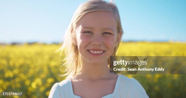 smile, portrait and child in field of flowers with blue sky, countryside and natural spring wellness. nature, happiness and face of girl in floral grass with peace, freedom and adventure with plants - anthony summers stock pictures, royalty-free photos & images