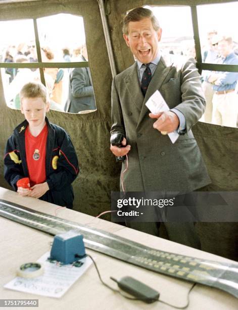 Britain's heir to the throne, The Prince of Wales roars with laughter as he crashes a Scalextric model during a visit to RAF Valley's Annual family...