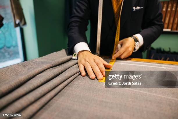 tailor using measuring tape on a desk - tailor stock pictures, royalty-free photos & images