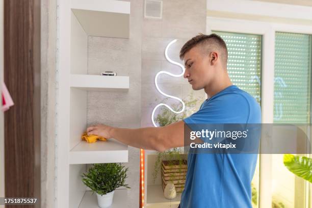 adolescente che fa le faccende domestiche - pulire la polvere - spolverare foto e immagini stock