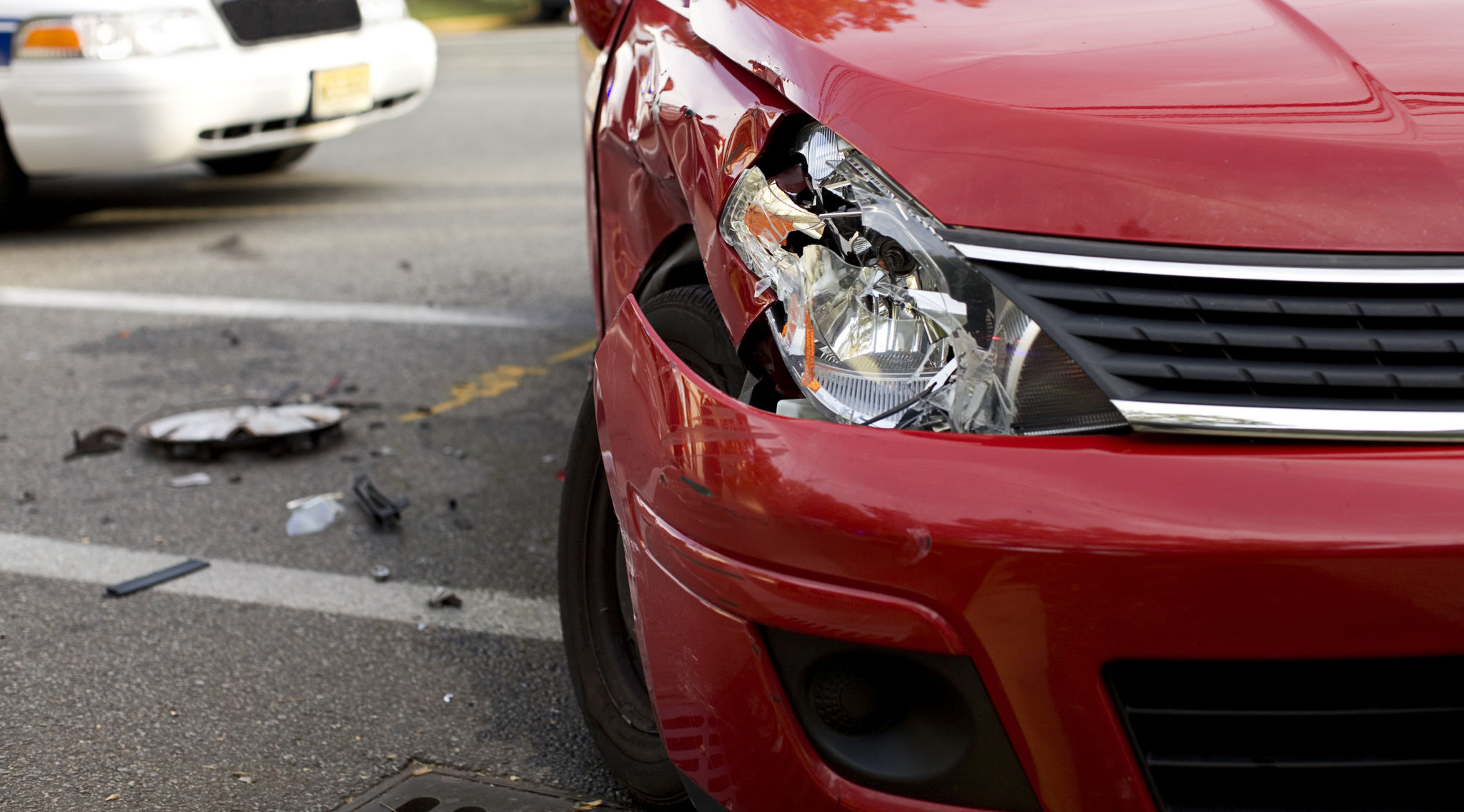 A red car with a damaged headlight after an accident A red car with a damaged headlight after an accident