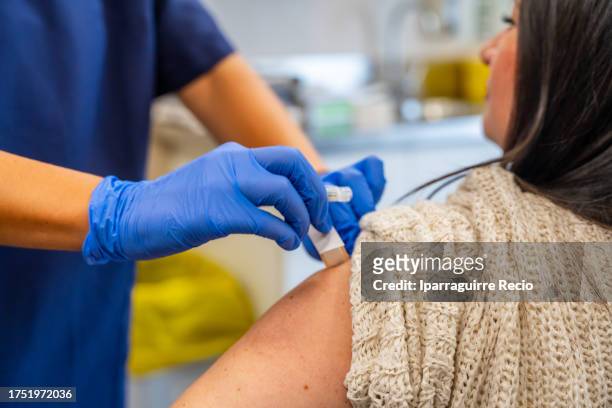 hands of an unrecognizable nurse injecting the injection for flu vaccination campaign in a medical center to fight winter diseases - vaccino antinfluenzale foto e immagini stock