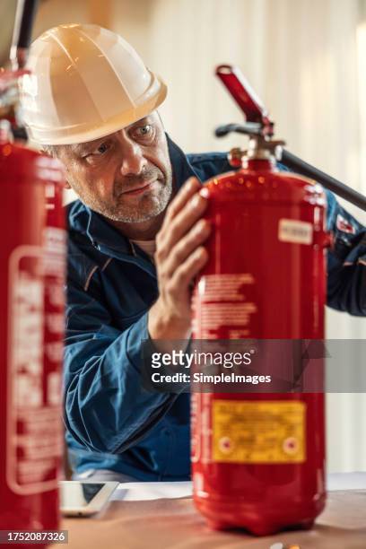 a professional safety inspector checks the fire extinguishers in the hotel restaurant. - fire extinguisher inspection stock pictures, royalty-free photos & images