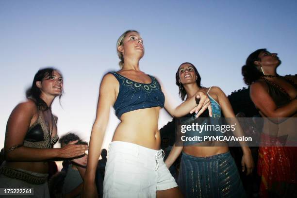 Four cute hippy girls dancing, Sunset beach party, Benirras Beach, Ibiza, July 2006.