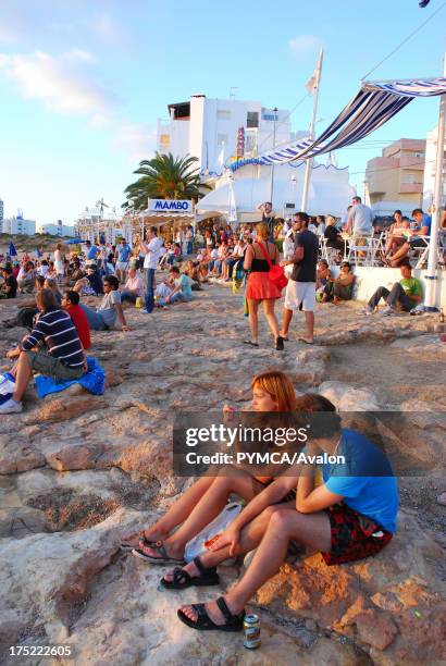 People sat on the beach outside Cafe Del Mar, San Antonio, Ibiza.