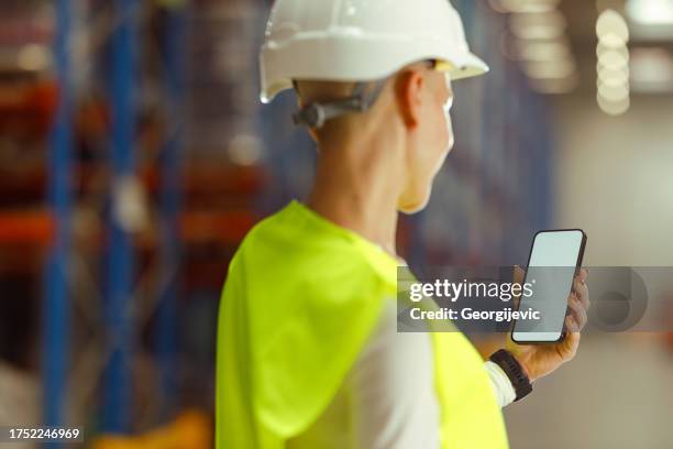 caucasian female warehouse worker is using smartphone - screen protector stock pictures, royalty-free photos & images