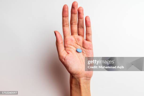 a womman's hand holding a pill with a wood floor as background - handfläche stock-fotos und bilder