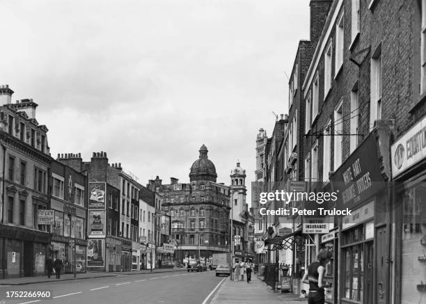 The view north along the shops on St John Street with traffic waiting at the junction of Pentonville Road and City Road , in Angel, Islington,...