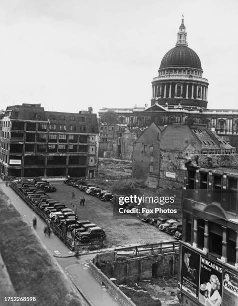 St Paul's Cathedral rises beyond a cleared bomb site, repurposed as a car park, with Cannon Street in the foreground, in the City of London, England,...