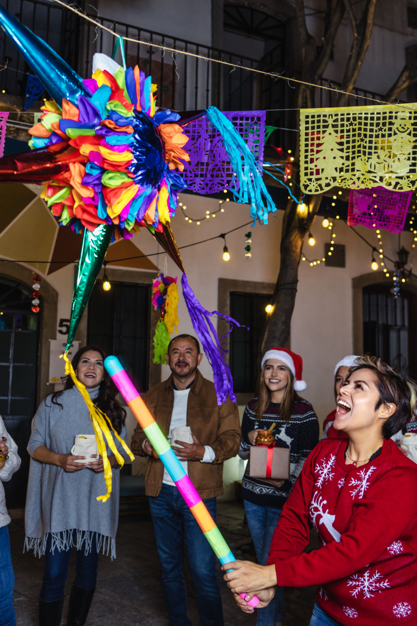 Mexican family breaking a piñata at traditional posada party for Christmas in Mexico Latin America, hispanic people Mexican family breaking a piñata at traditional posada party for Christmas in Mexico Latin America, hispanic people