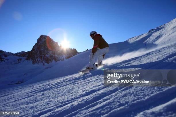 Snowboarder rides at speed down a deserted piste as the sun sets in Tignes, FRANCE. .