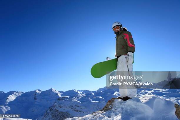 Snowboarder enjoys the elevated view from the top of a peak in the Espace Killy, Tignes, FRANCE. .