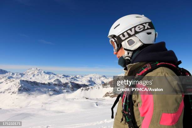 Snowboarder looks down at the valley an mountain ranges beyond, which are reflected in her goggles, Espace Killy, Tignes, FRANCE. .