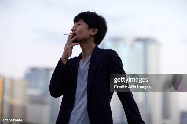 japanese man smoking outside - zigarettenpause stock-fotos und bilder