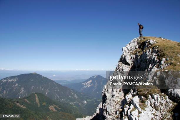 Hiker stands admiring the view from the peak of the mountain he has hiked in Triglav National Park, in the Julian Alps, SLOVENIA. .