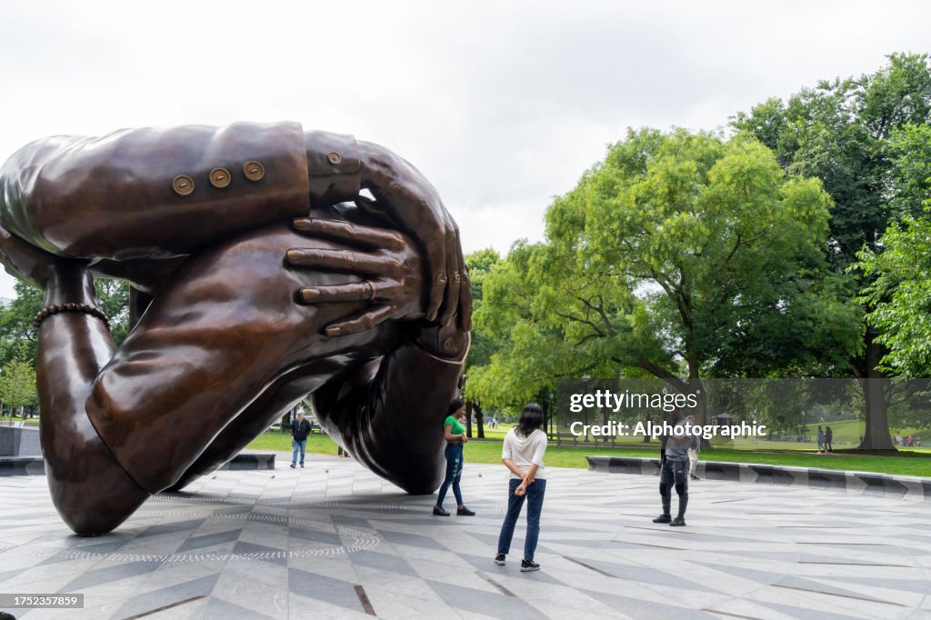 La scultura dell'abbraccio con il turista intorno.